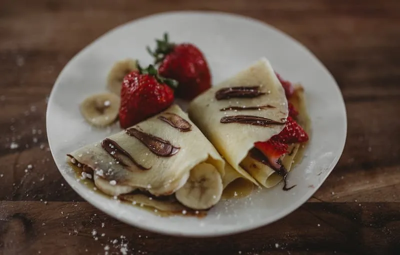 crepes dan buah strawberry di atas piring putih