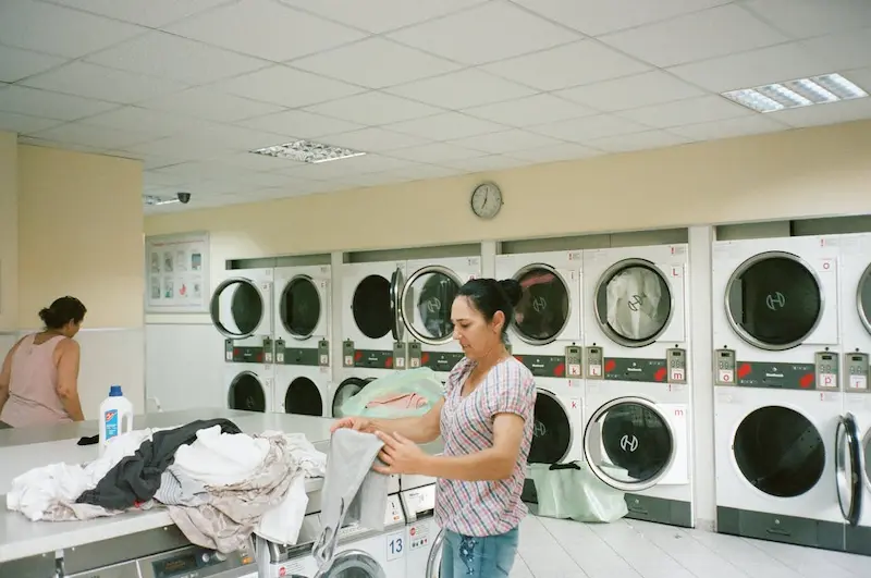 seorang ibu-ibu sedang merapikan baju di laundry