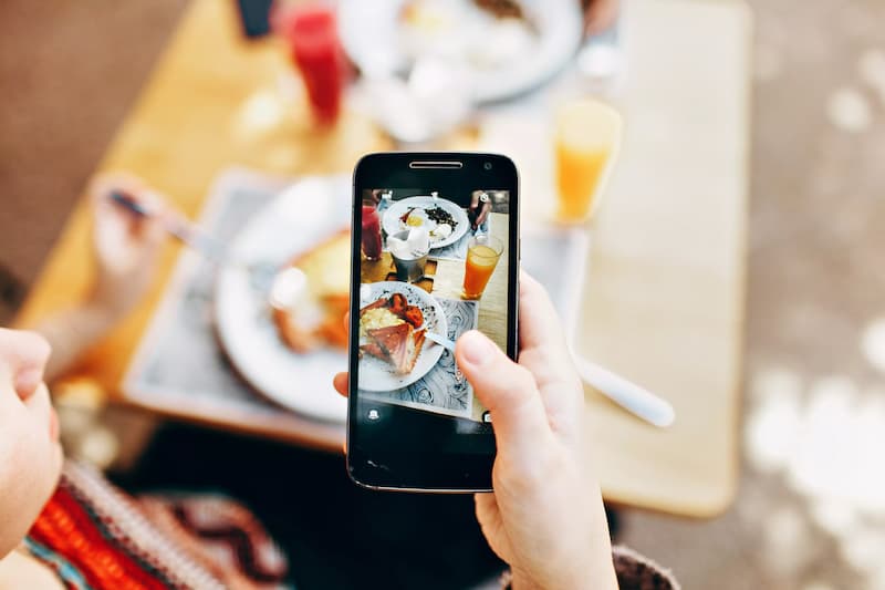 seseorang memotret makanan menggunakan handphone