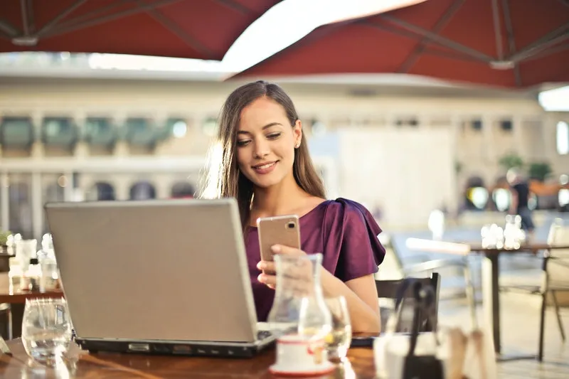 seorang wanita menatap layar handphone sambil tersenyum