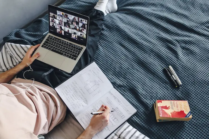 seseorang sedang belajar di laptop sambil menulis di buku